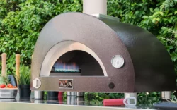Alfa moderno 1 pizza hybrid uppställd på uteköksbänk med gasolbrännaren fullt påslagen. Stämningsfull bild av en Italiensk pizzaugn