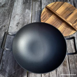 Wokpanna gjutjärn Omberg är en lagom stor svart wokpanna i materialet gjutjärn. Ett bra lock i trä medföljer